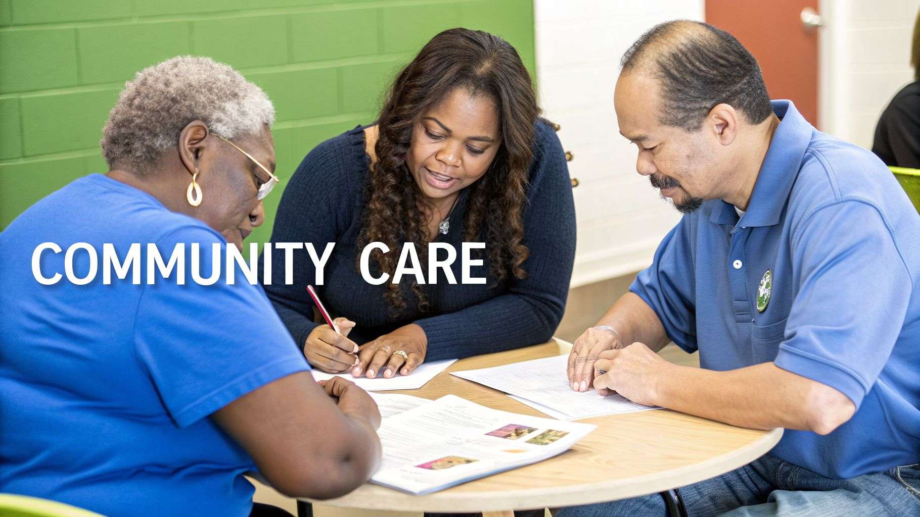 Three diverse adults engaged in a community care meeting, reviewing documents and writing.