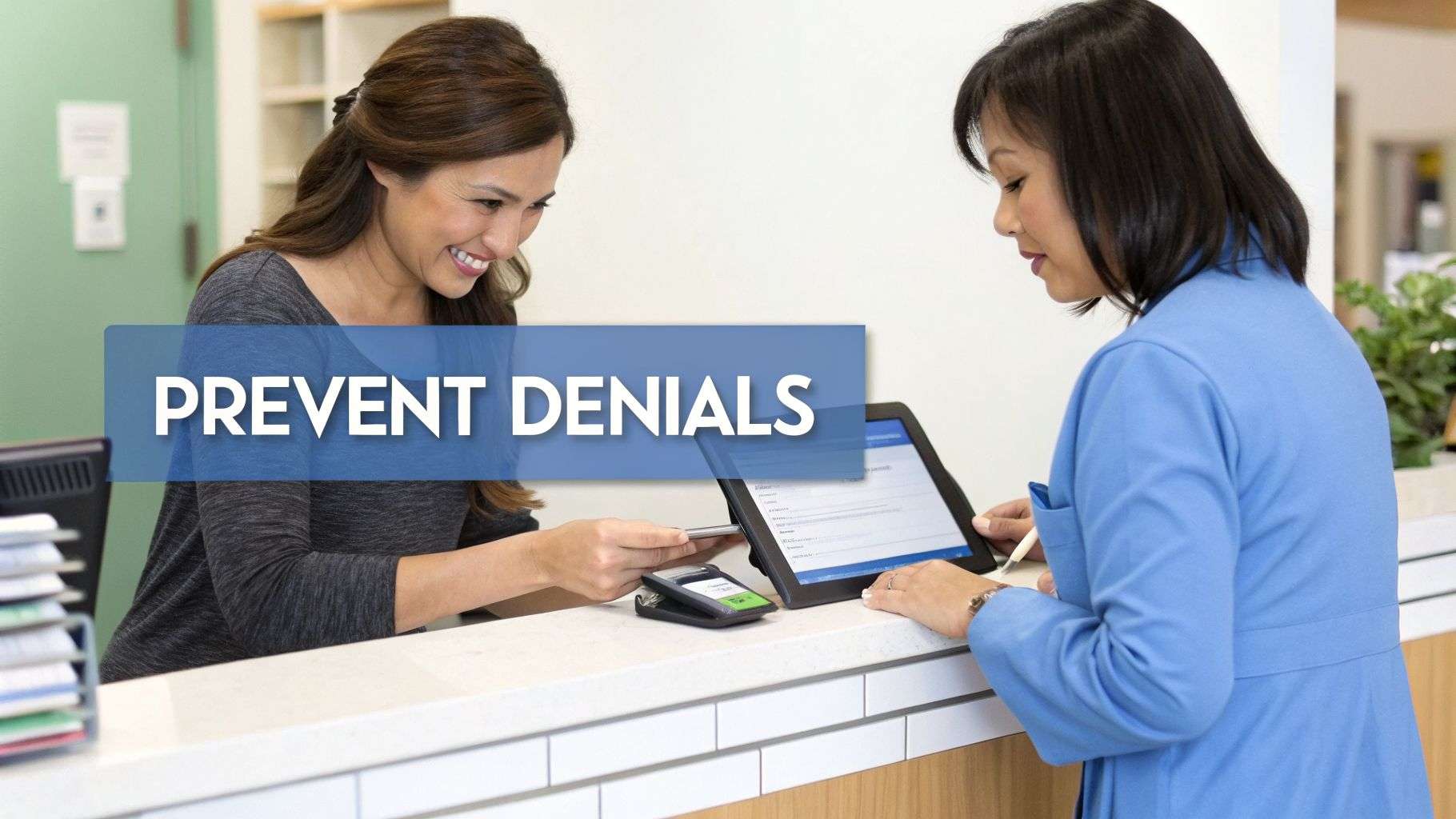 Two women at a healthcare reception desk using a tablet and payment terminal to prevent denials.