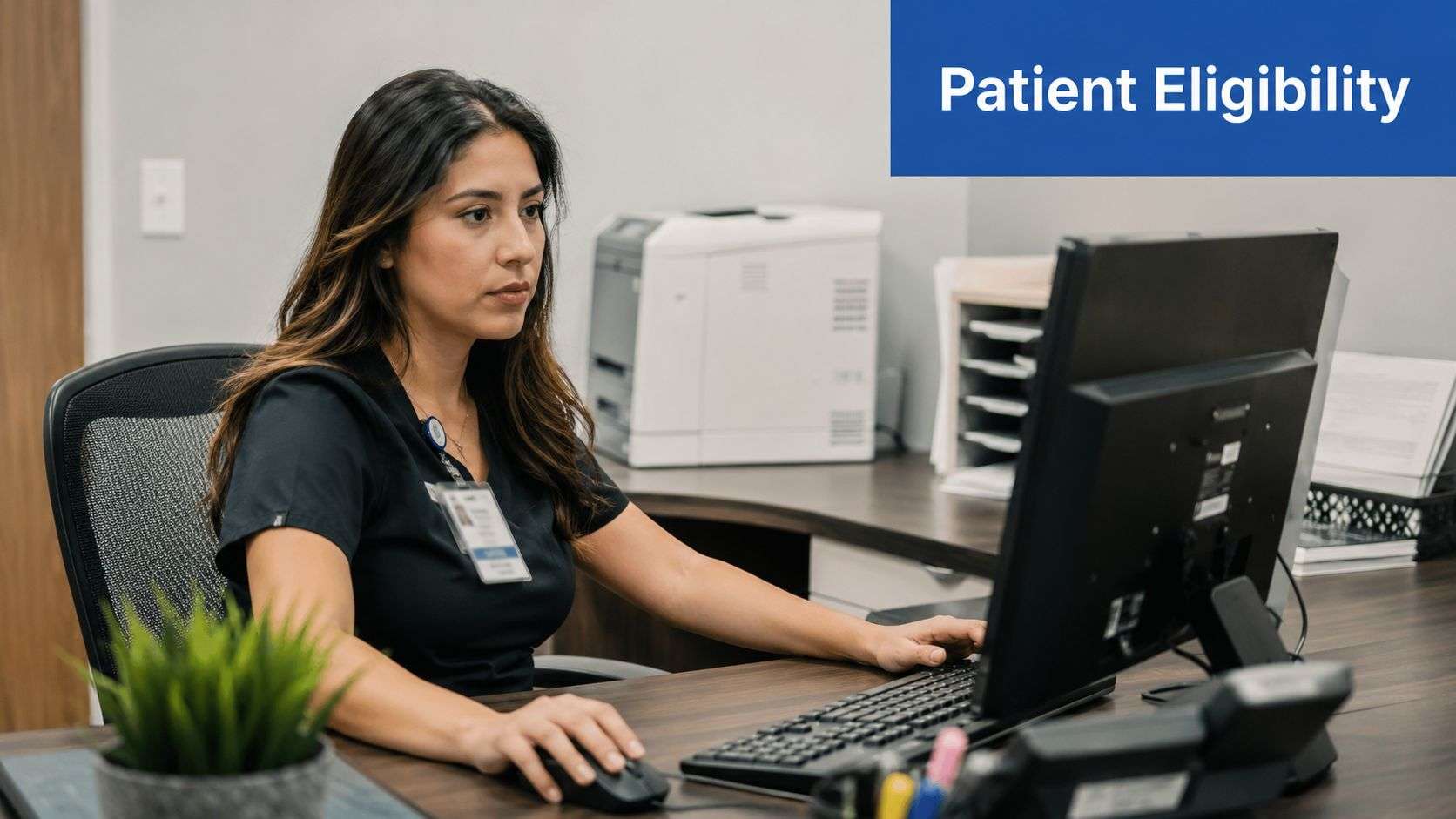 A professional medical administrative assistant verifying patient insurance eligibility at her desk in an office.