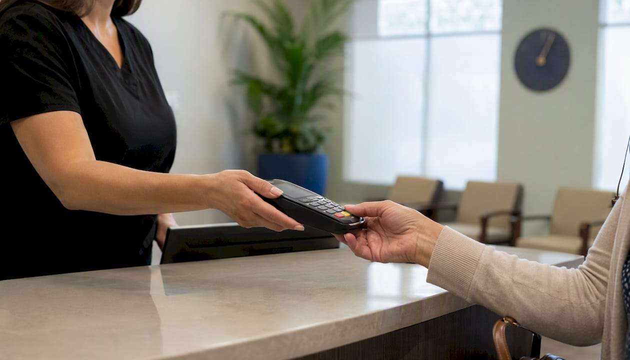 Hands exchanging payment terminal at clinic desk