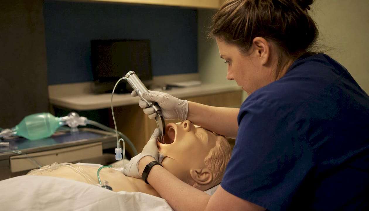 Hands performing intubation procedure on manikin